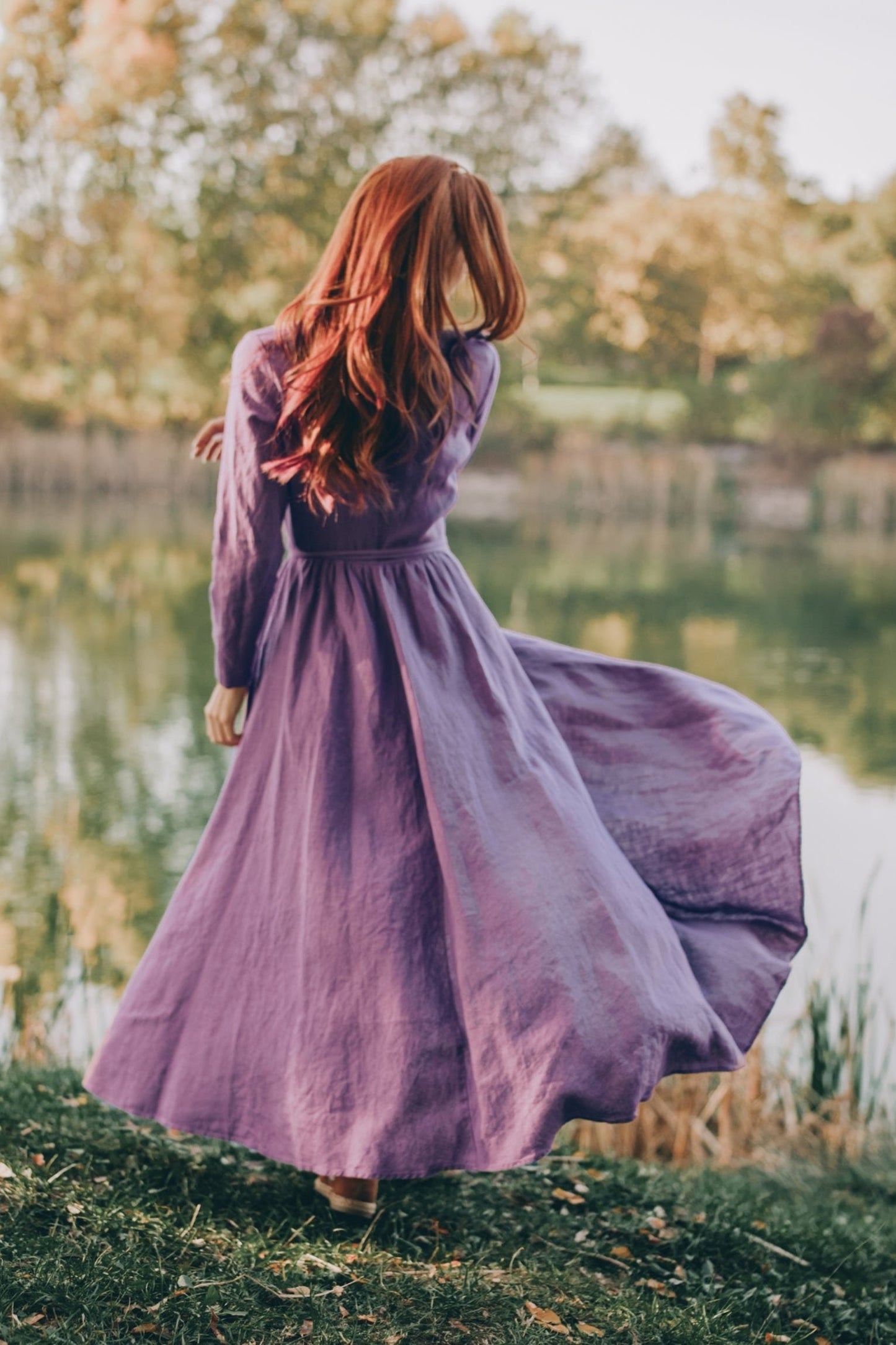 Woman wearing lavender wrap linen maxi dress with tie waist standing near lake outdoors