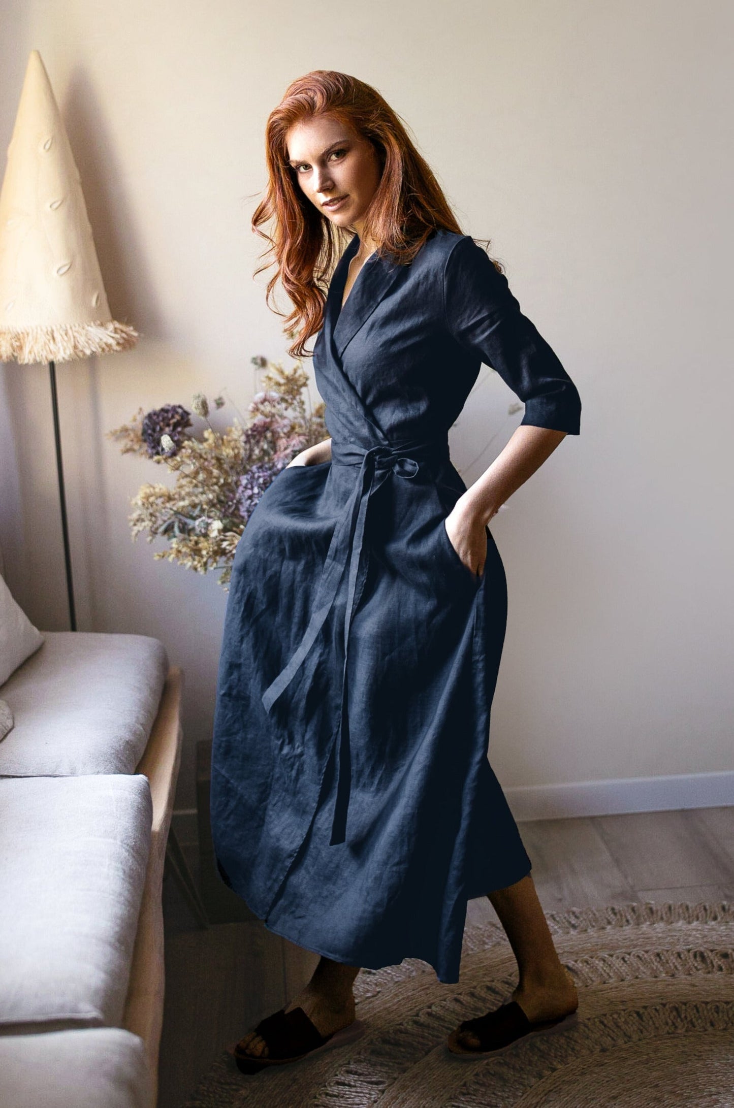 Woman wearing a navy midi length linen dress with tie waist standing indoors