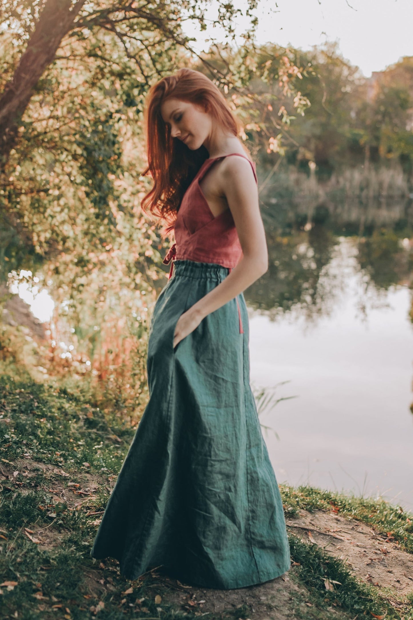 Woman wearing heavyweight linen maxi skirt with pockets standing by lakeside in natural setting