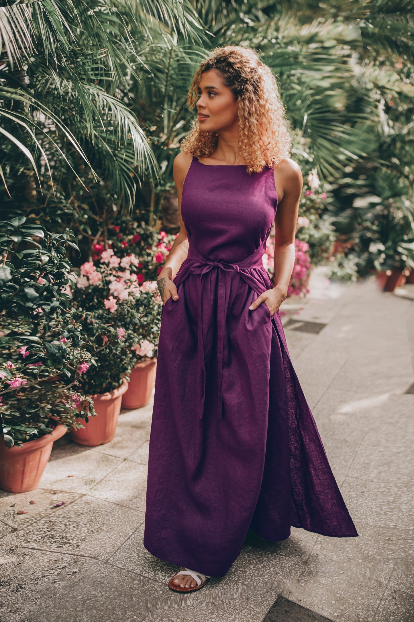 woman wearing purple double wrap linen maxi dress outdoors with greenery and flowers