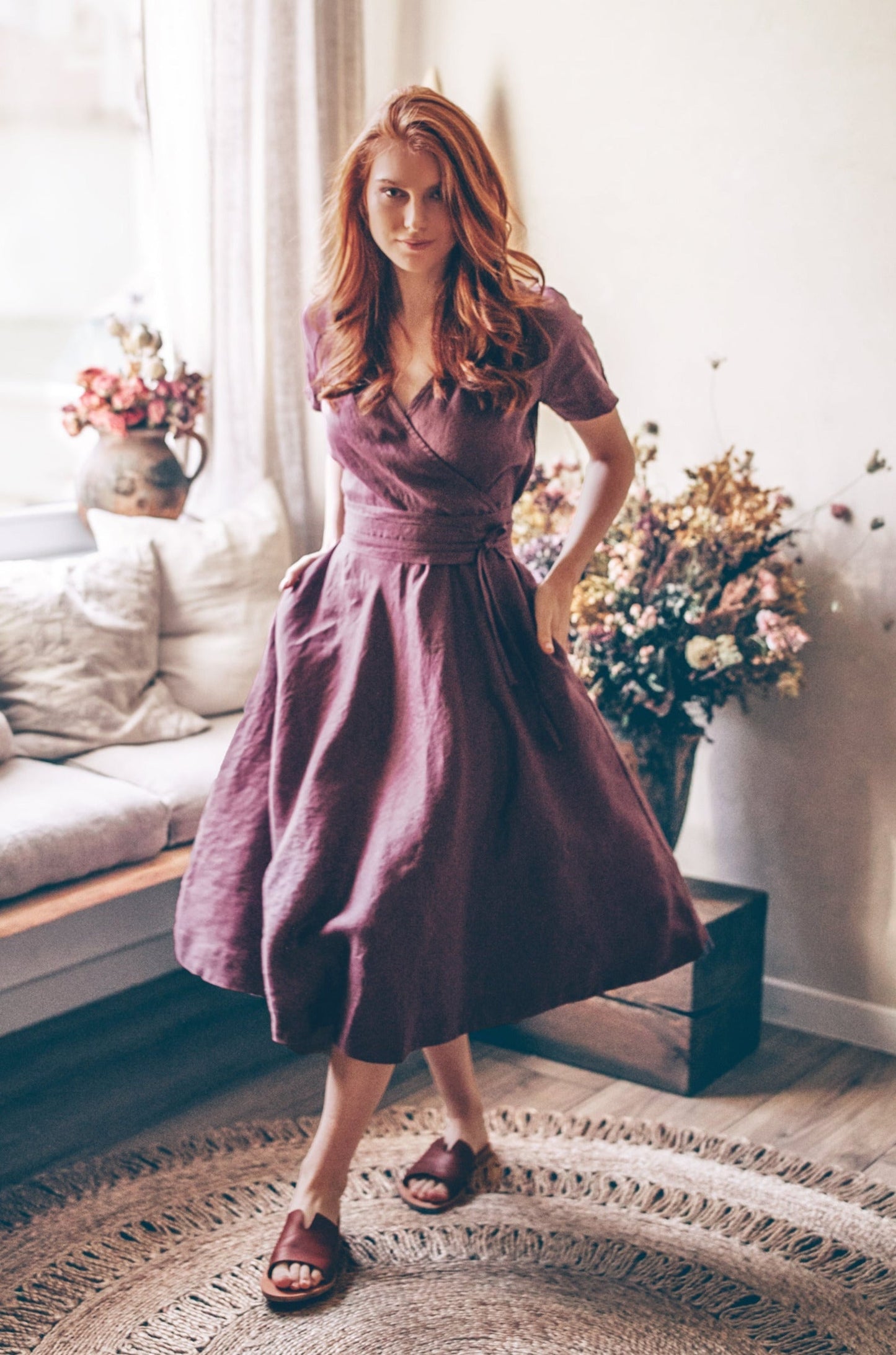 woman wearing midi length linen wrap dress with surplice neckline and side pockets indoors