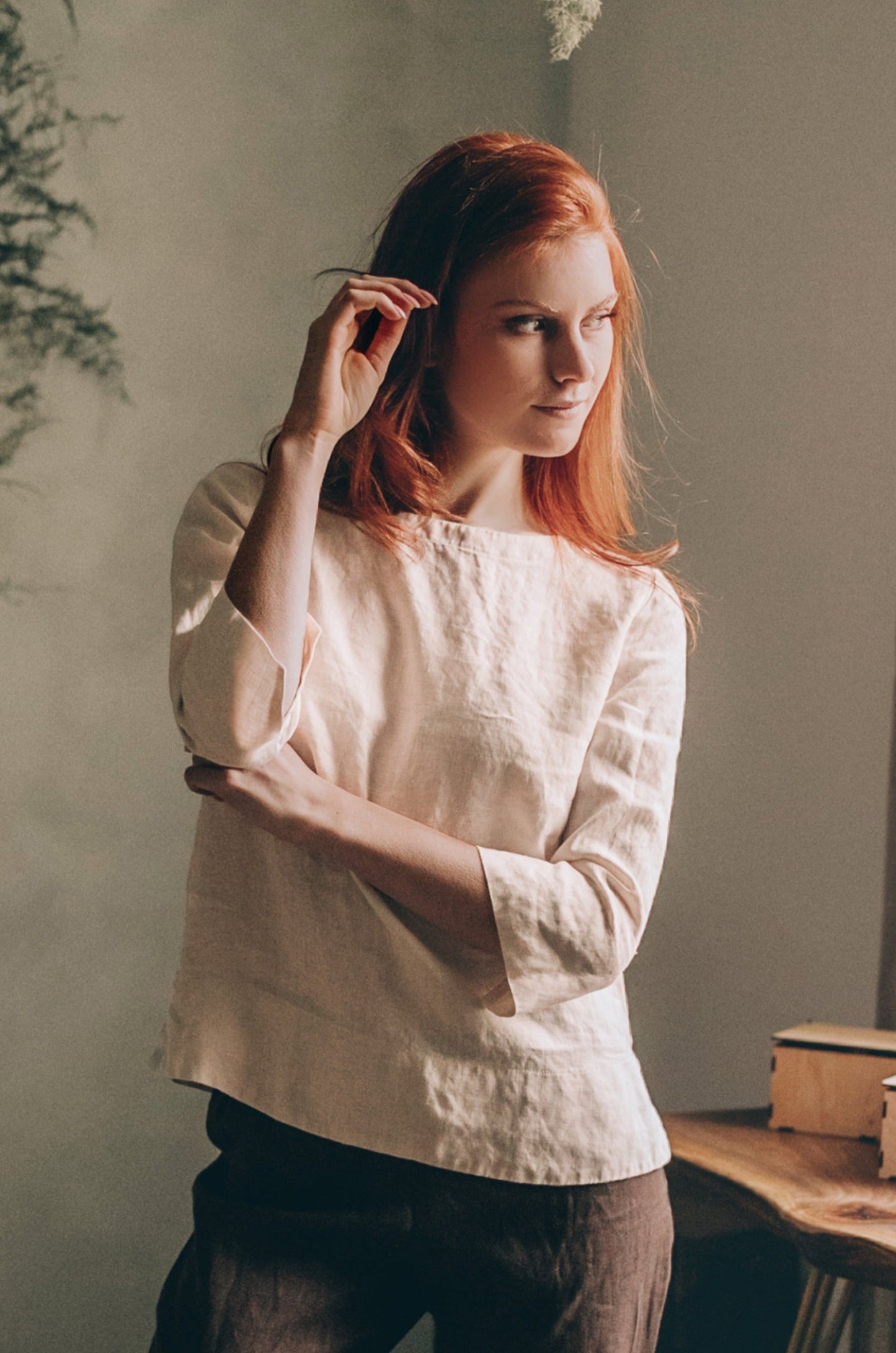 Woman wearing cream linen staple top with three-quarter sleeves in relaxed fit