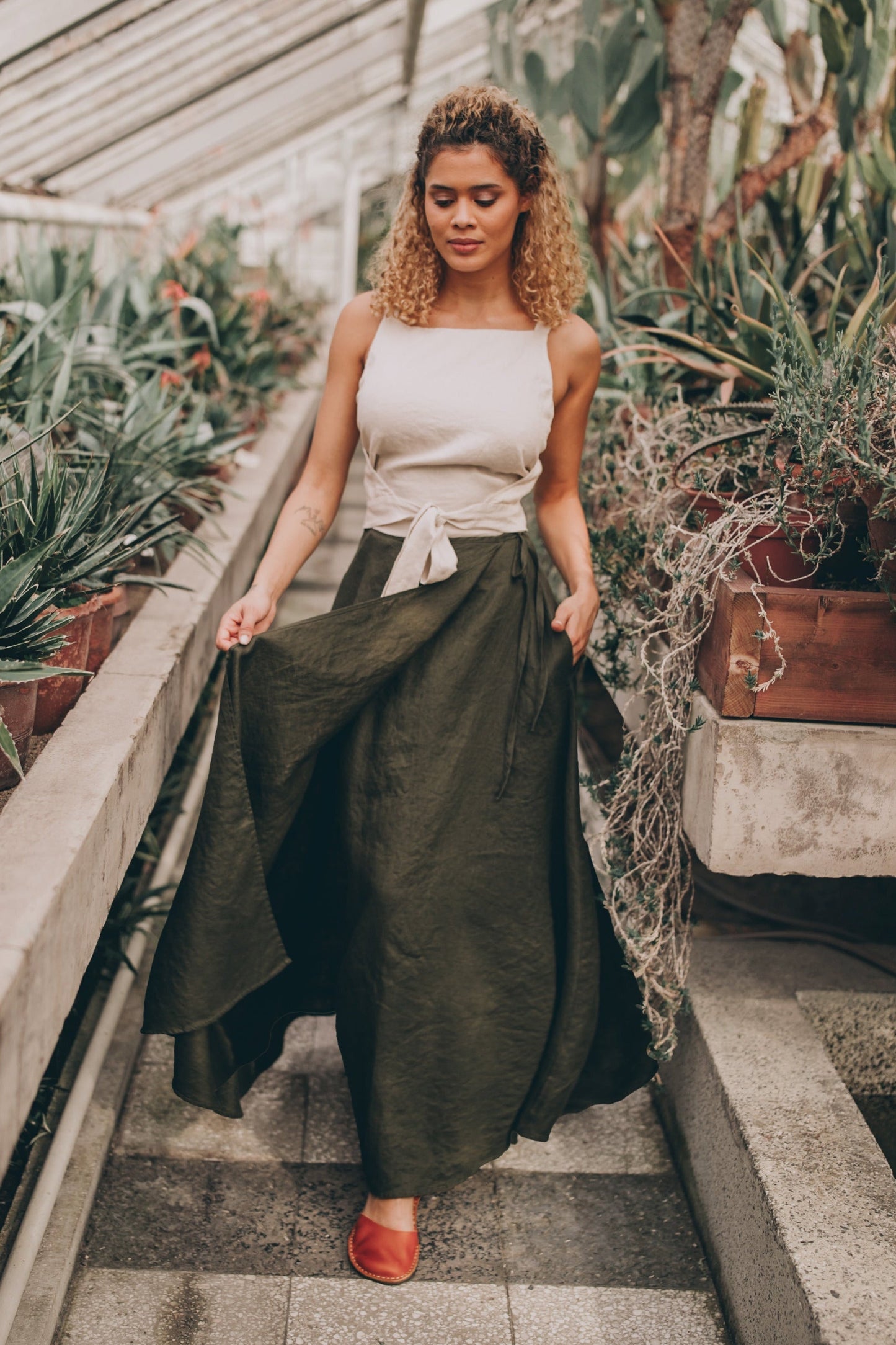 Woman wearing flared linen wrap maxi skirt with pockets in outdoor garden setting