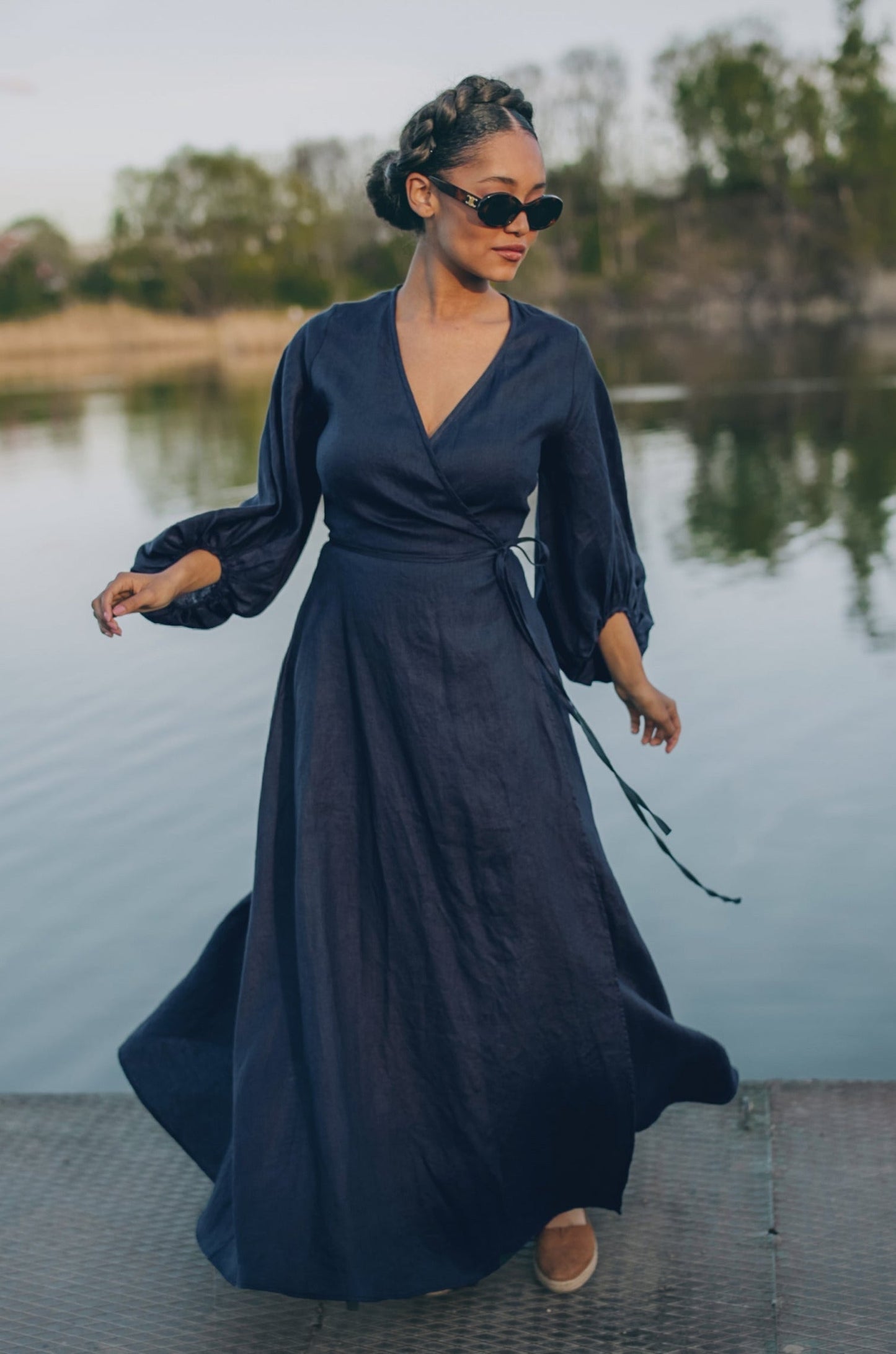 Woman wearing night blue linen maxi dress with puff sleeves and tie waist by the water