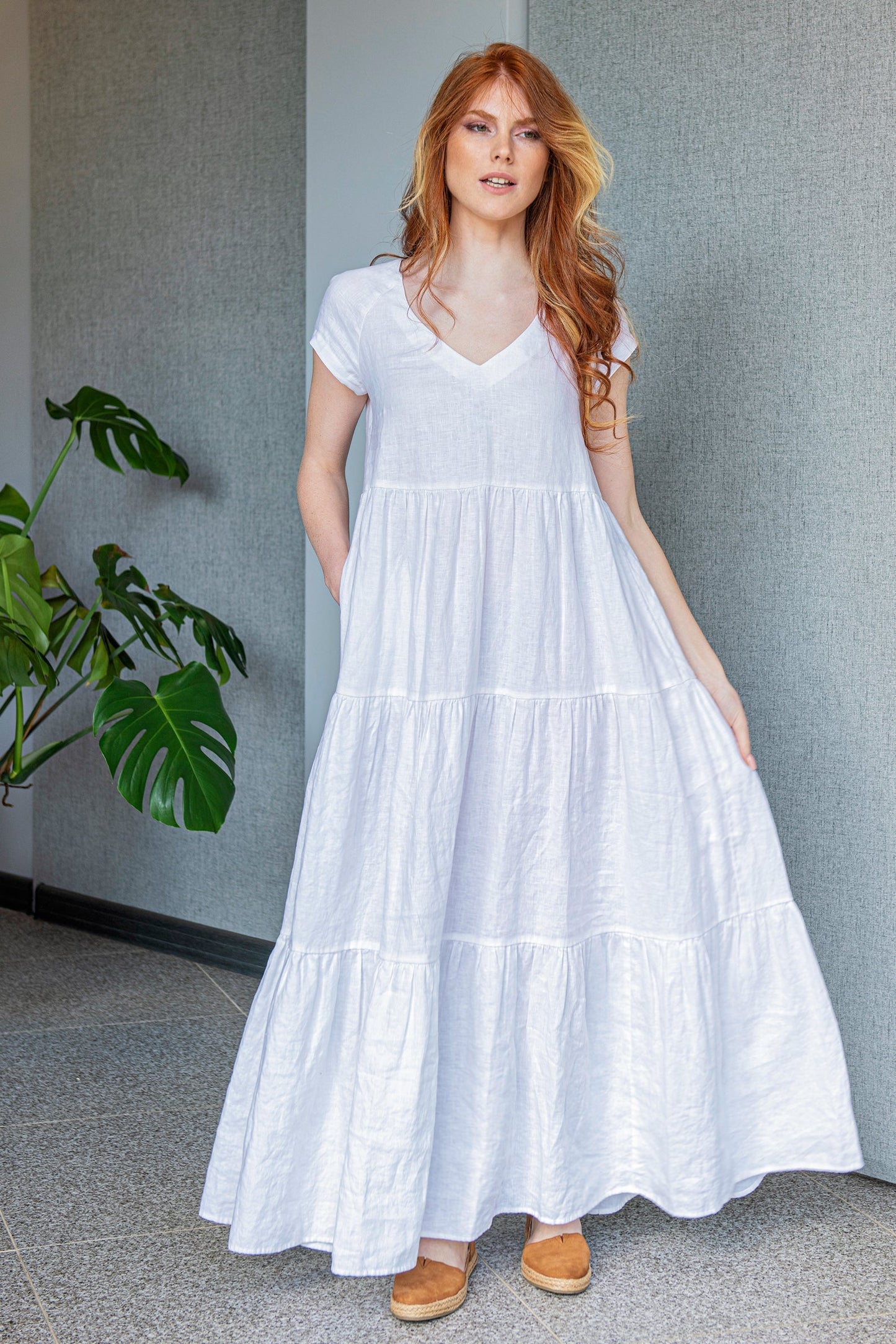 woman wearing white bohemian linen dress with tiered skirt and short sleeves indoors