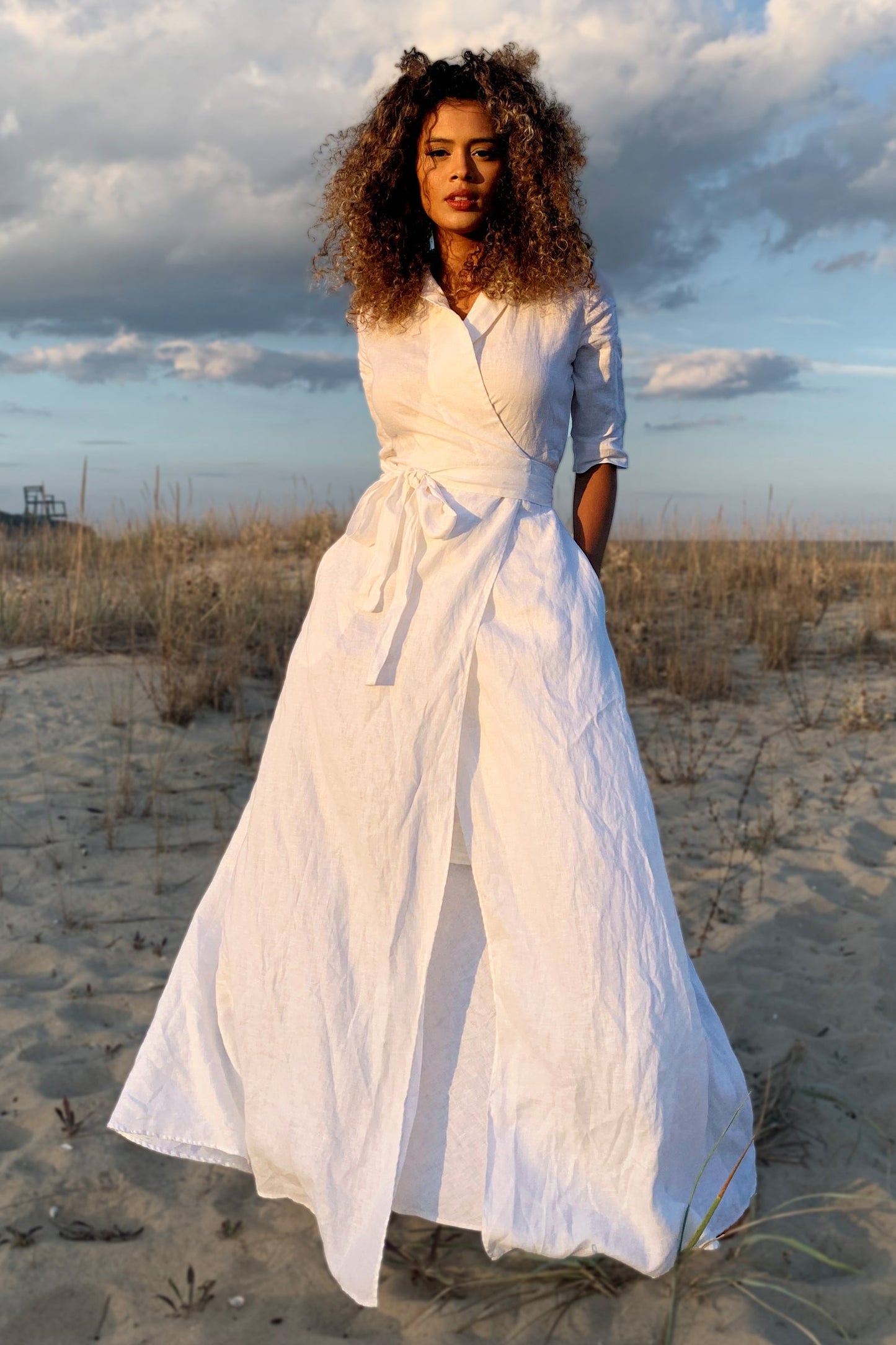 woman wearing white maxi linen dress with tie waist standing on beach