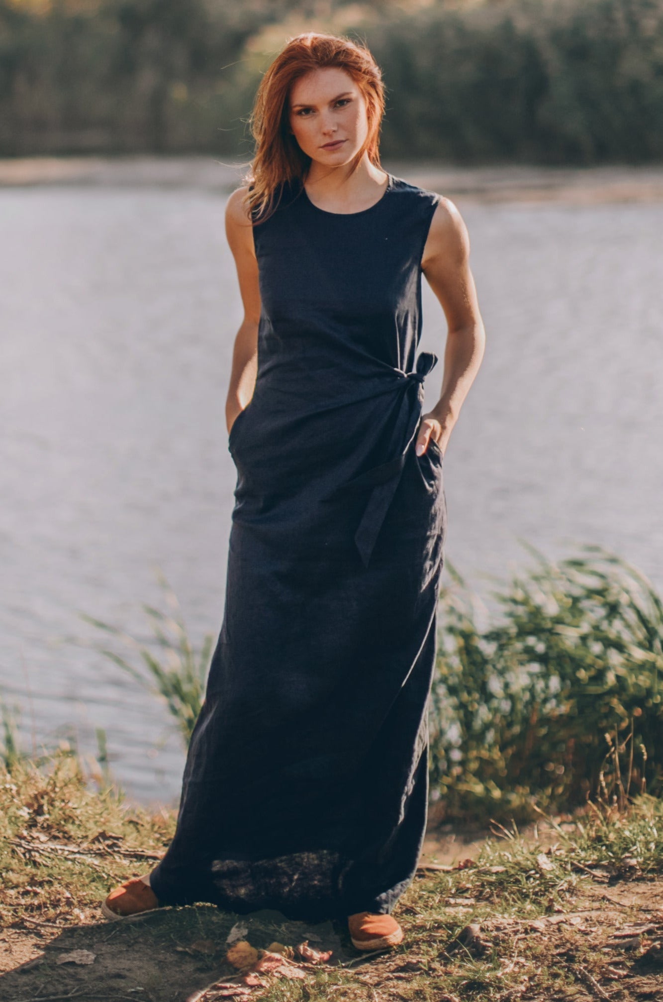 Long linen dress in navy blue with ruched waist and side pockets worn outdoors
