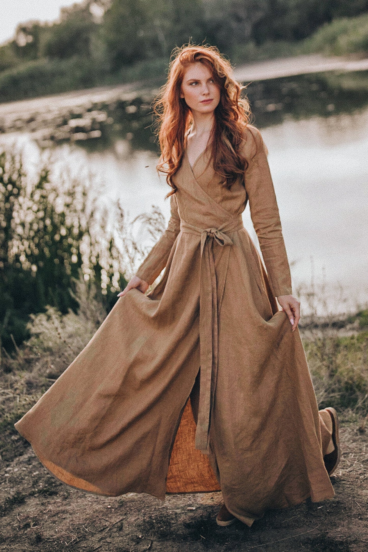 Woman wearing camel rich linen wrap dress with long sleeves and tie belt by the lakeside