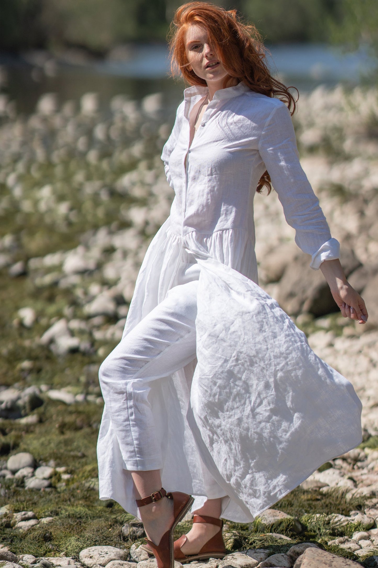 Woman wearing long white linen tunic shirt with rolled sleeves by the beach