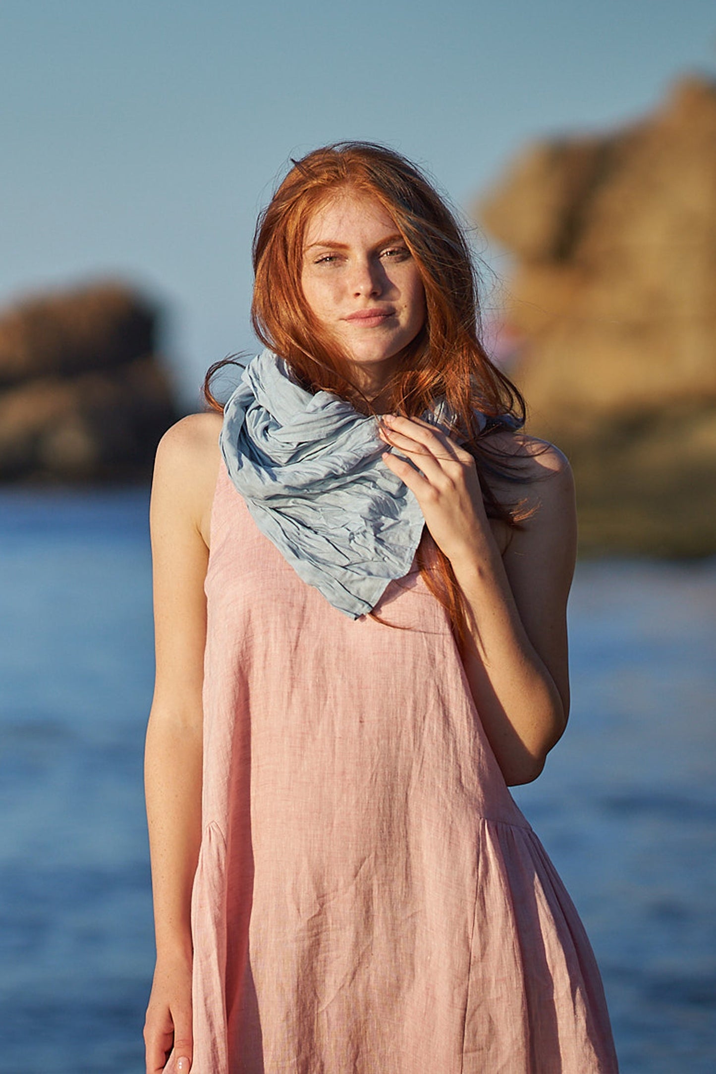 woman wearing light blue linen scarf at the beach
