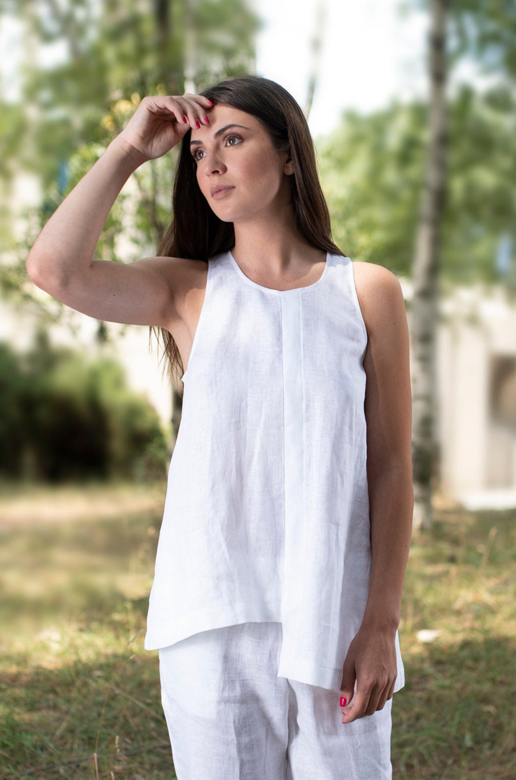 woman wearing white linen tank top with asymmetric hem standing outdoors