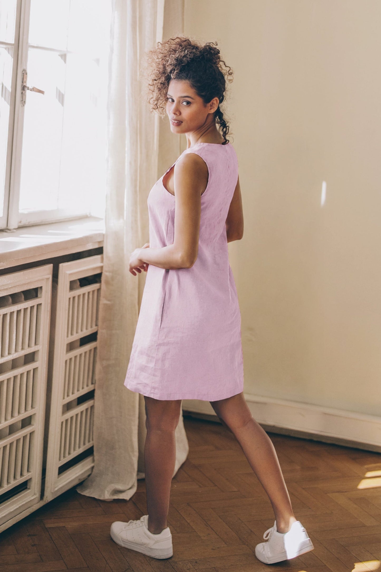 Woman wearing breezy linen dress standing outdoors in summer sunlight