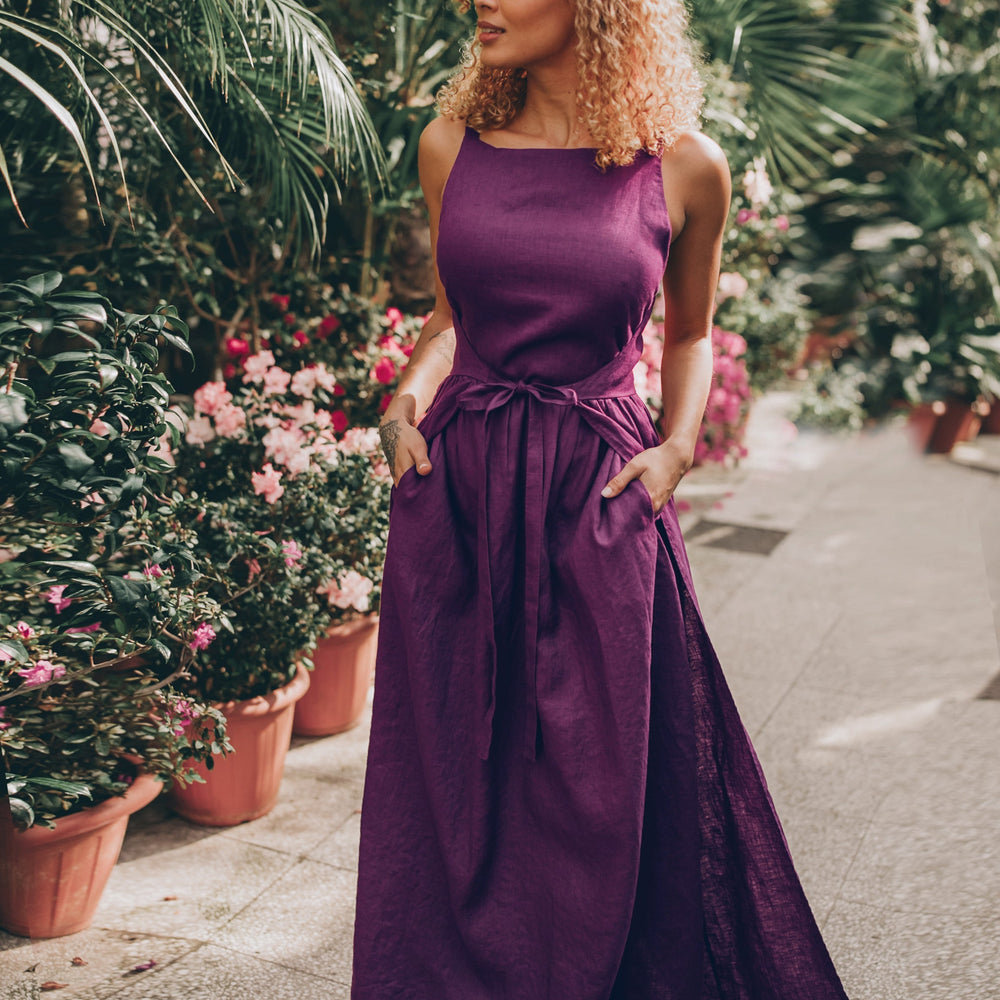 Double wrap linen maxi dress in purple worn by a model outdoors with lush greenery.