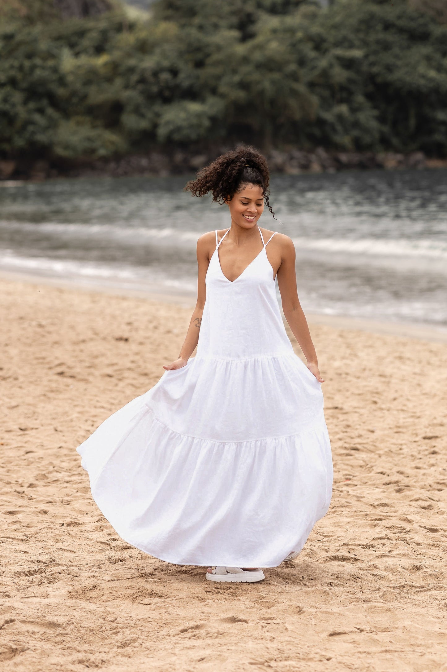 Elegant cream tiered linen maxi dress with pockets and adjustable straps, perfect for summer.