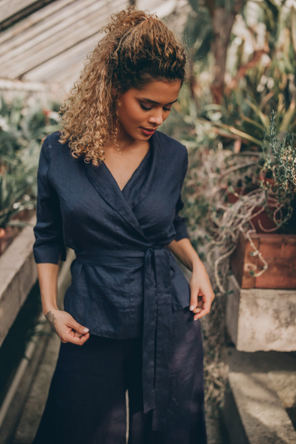 Linen wrap top with shawl neck and tie belt, featuring elbow length sleeves, styled with dark pants.