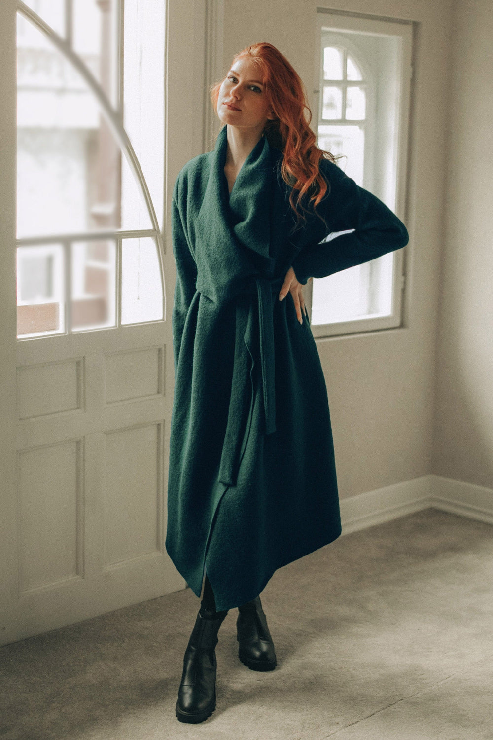 Woman wearing draped wool cardigan coat with belted wrap and waterfall front indoors