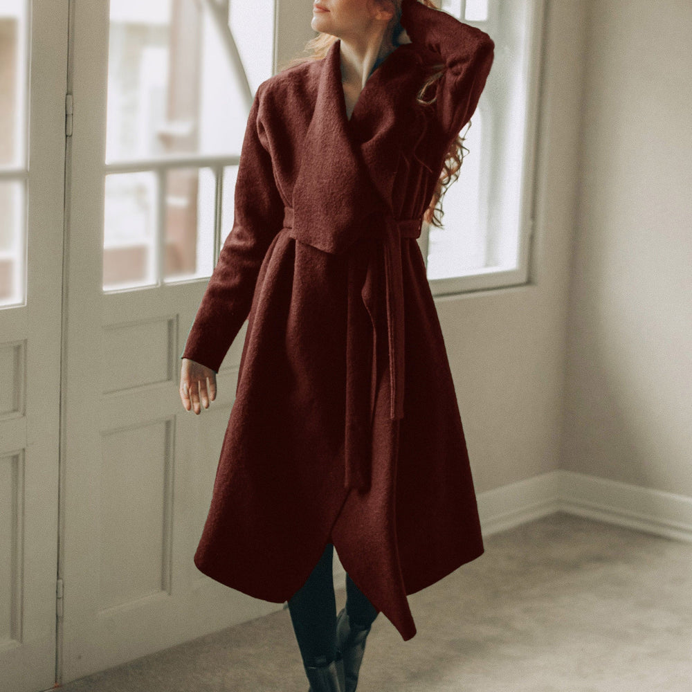 
                      
                        Woman wearing a long brown cardigan coat in a room with large windows.
                      
                    