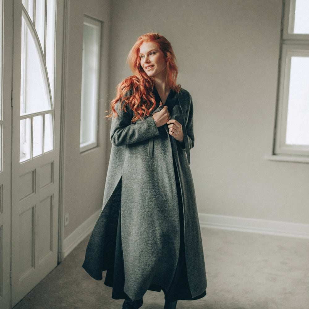 
                      
                        Woman with red hair standing in a room with neutral walls and a door.
                      
                    