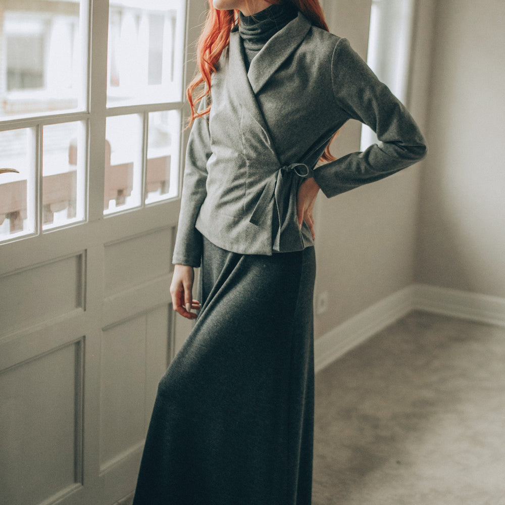 
                      
                        Woman in a gray wool cardigan tanding by a window in a well-lit room
                      
                    