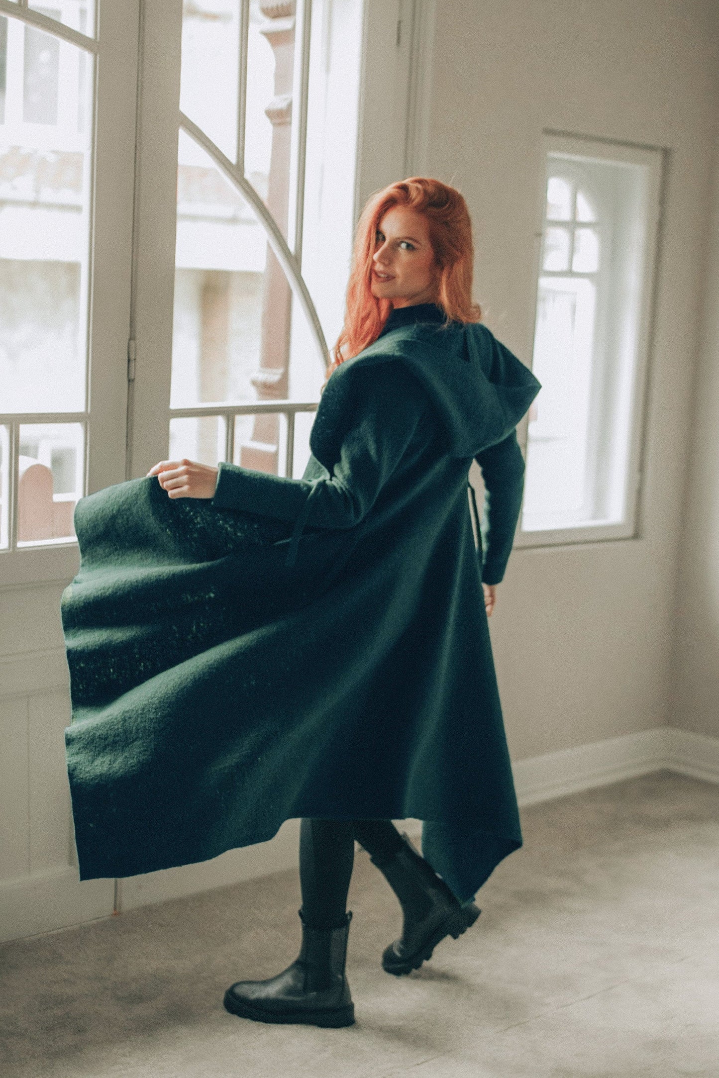 woman wearing emerald green asymmetrical wool cardigan coat with hood indoors