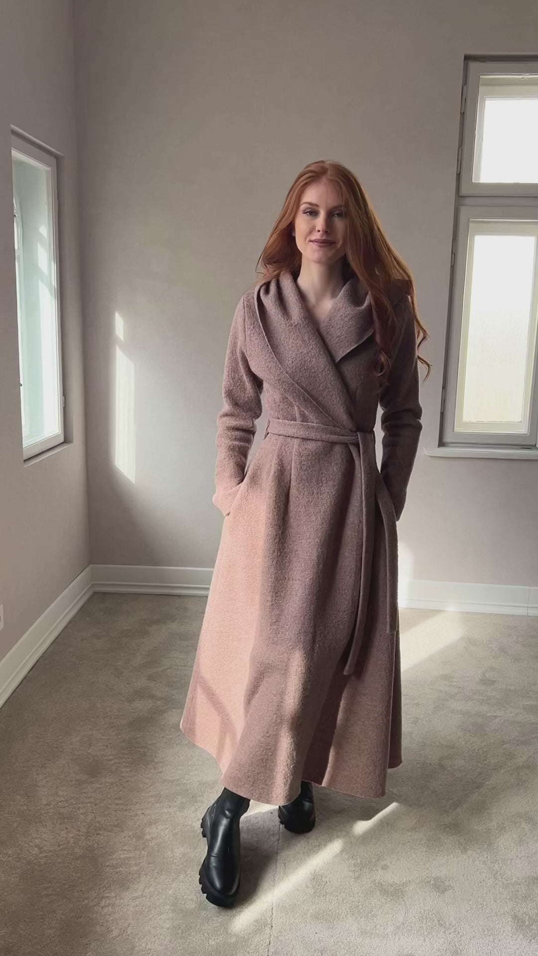 Video of a handmade maxi wool blend cardigan coat with a hood, adjustable waist belt, princess-style silhouette, and deep side pockets, showing the fit, flowing design, and movement of the coat.