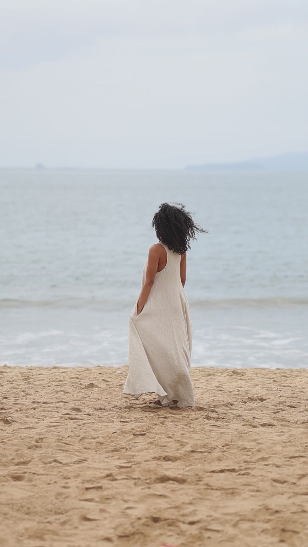 Woman wearing a linen maxi dress with side pockets and racerback design