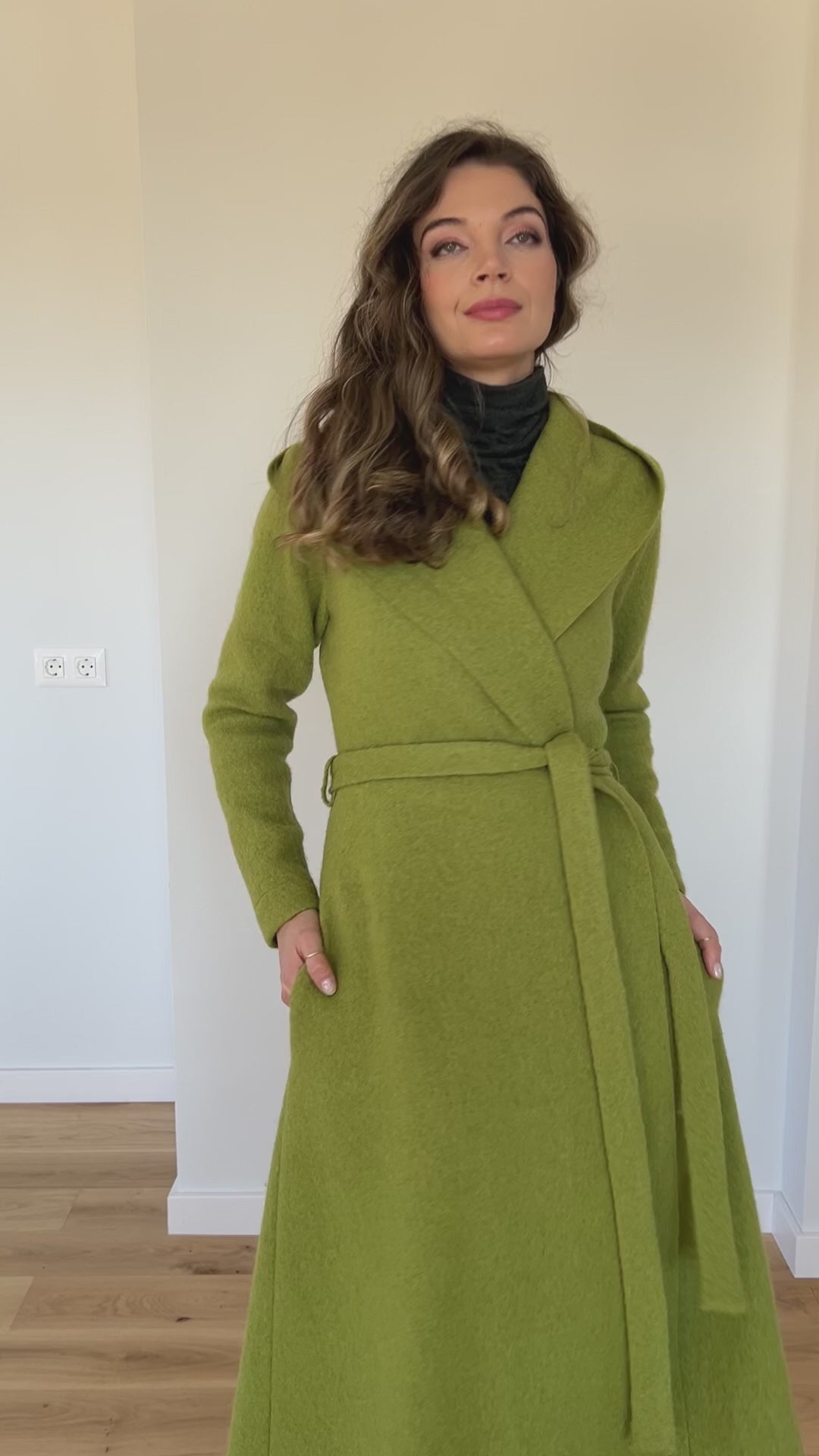 Video of a handmade maxi wool blend cardigan coat with a hood, adjustable waist belt, princess-style silhouette, and deep side pockets, showing the fit, flowing design, and movement of the coat.