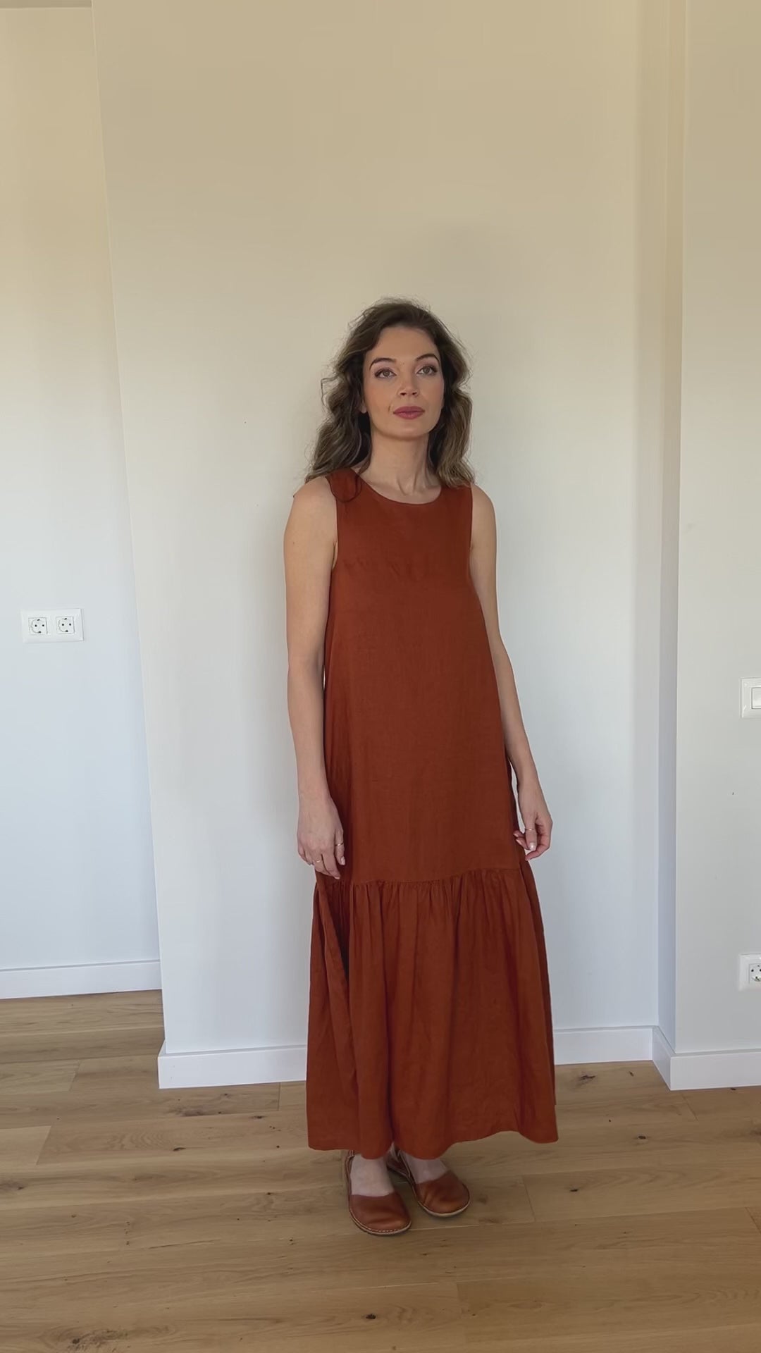Video of a sleeveless linen midi dress with a relaxed fit, flared hem, and side pockets, showing the silhouette and movement of the design.
