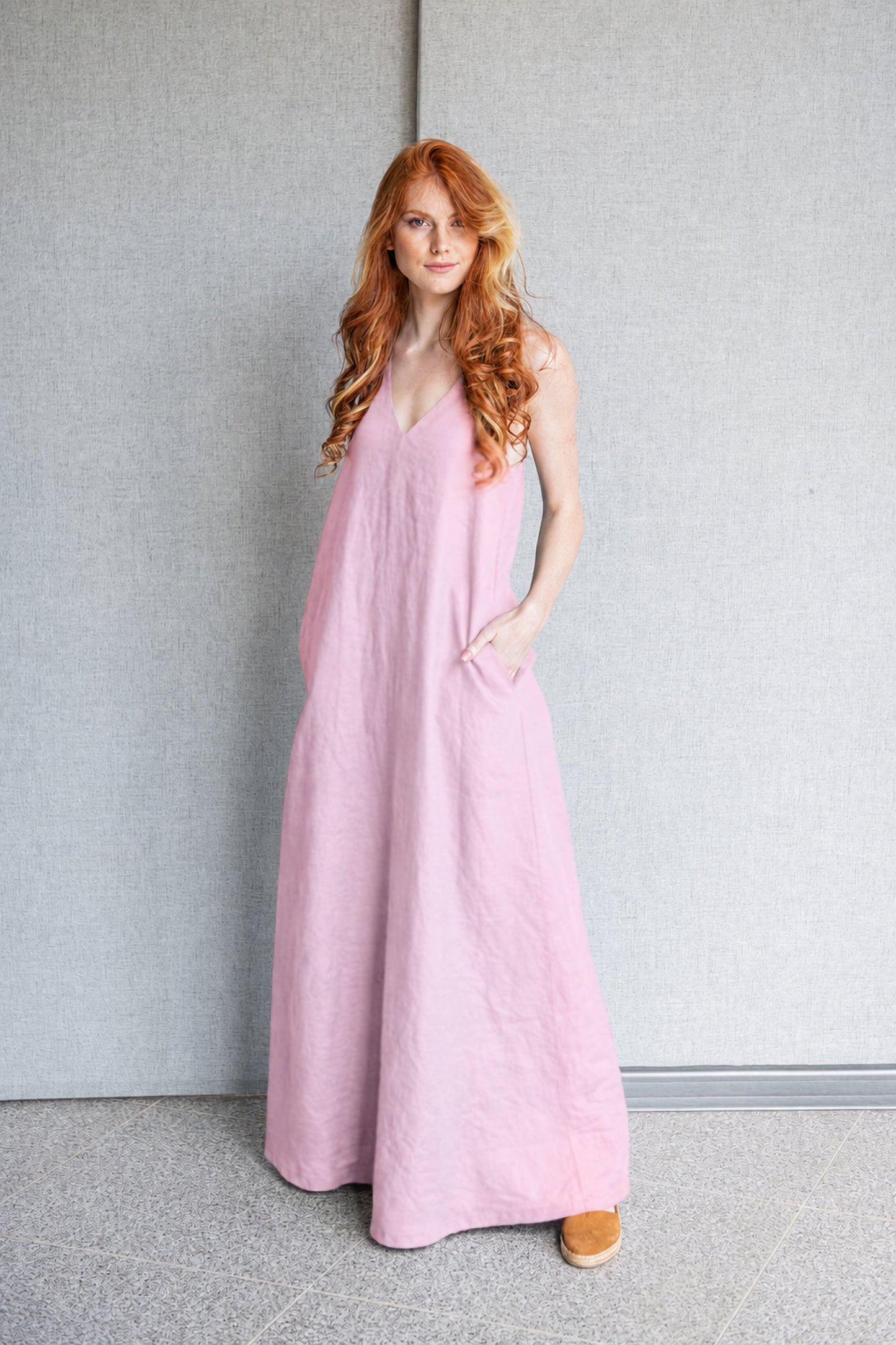 Minimalist linen sleeveless dress in pink with deep V-neck and halter back, worn by a model
