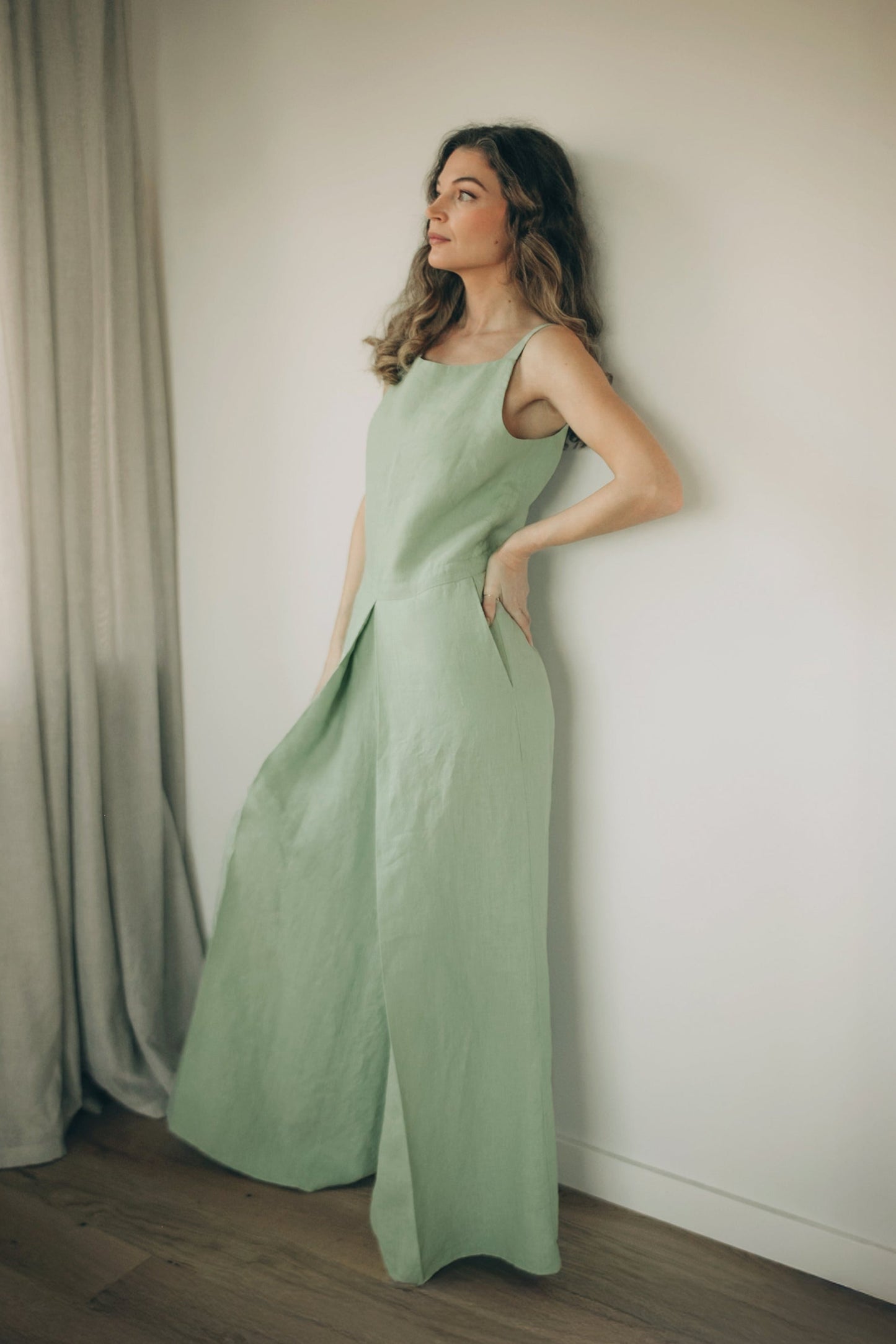 Woman wearing wide leg linen jumpsuit with pleated front and shoulder straps
