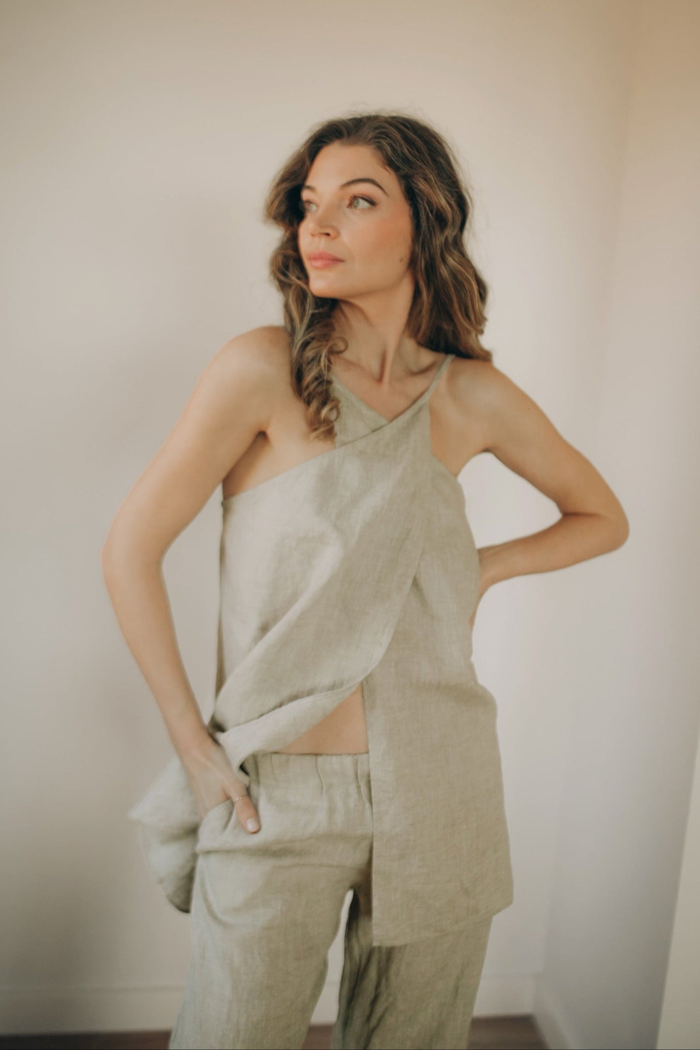 Woman wearing open back linen tunic top with cross-front neckline and thin straps