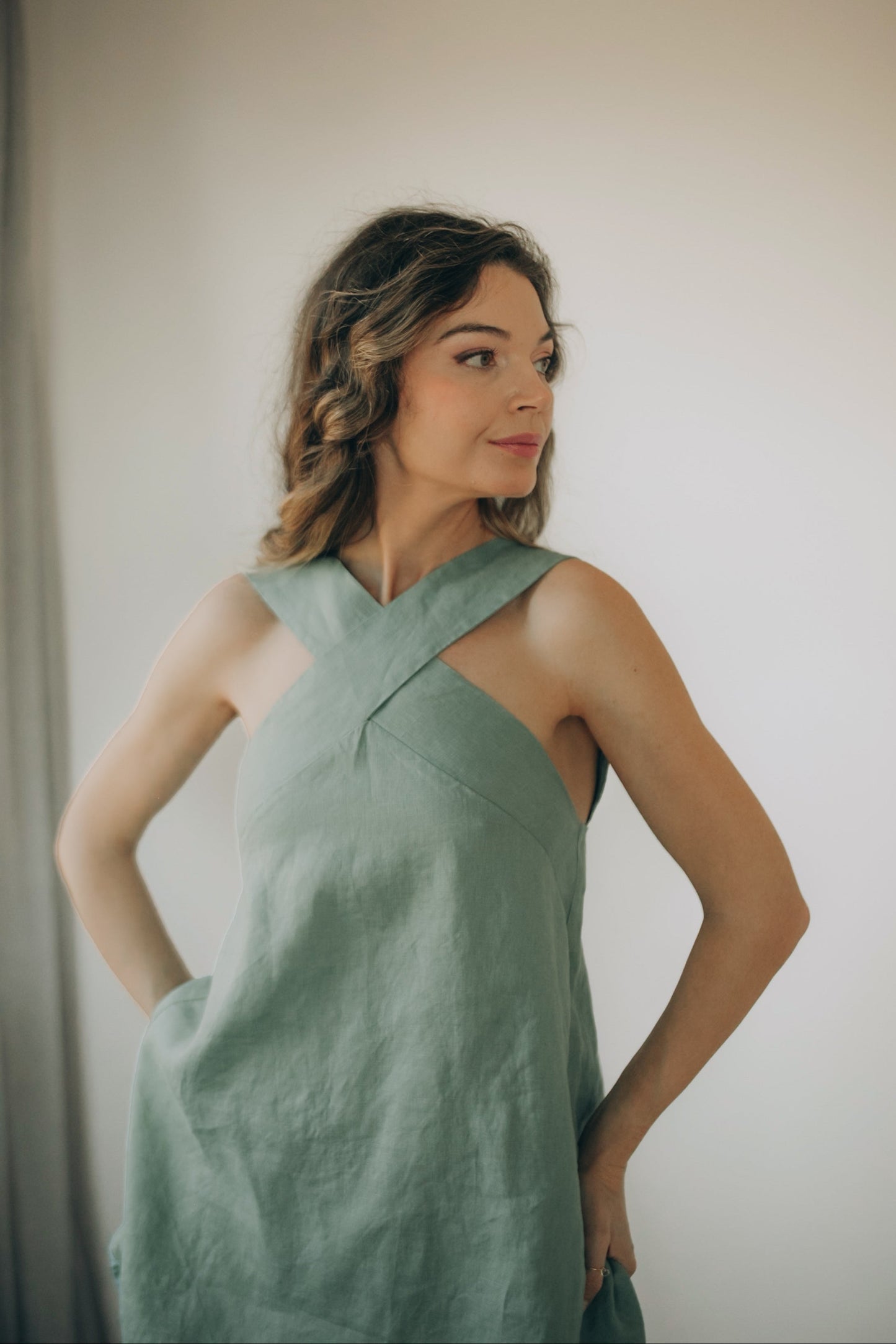 Woman wearing elegant cross-front linen tunic with open back and hidden zipper closure