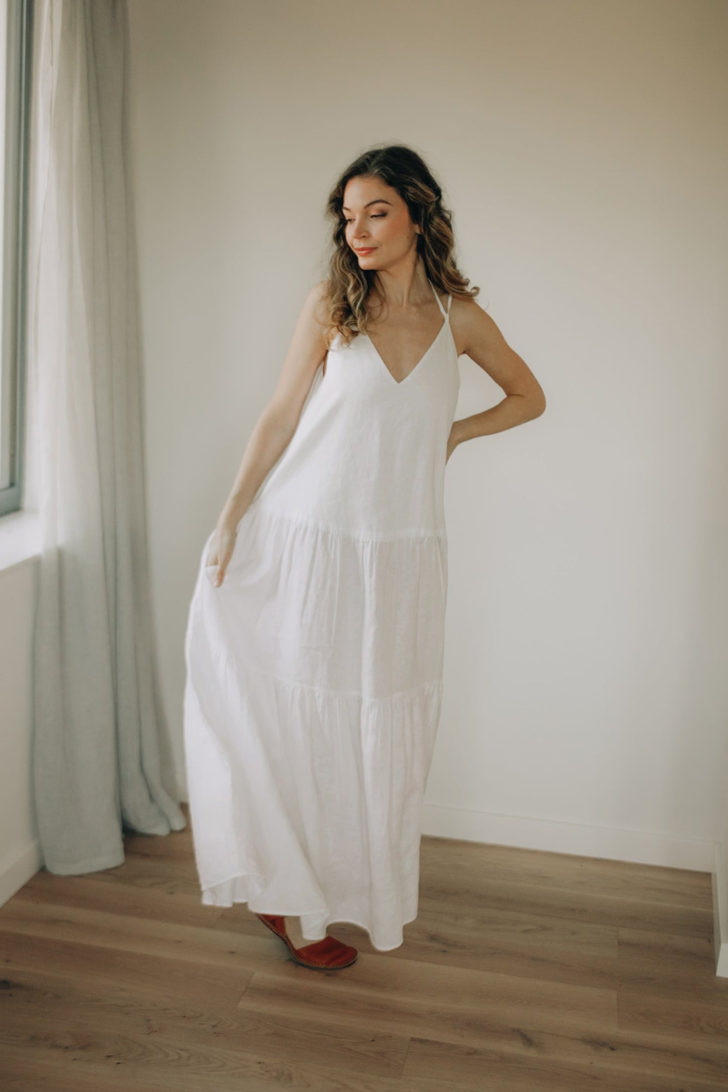 White ankle-length tiered linen dress with adjustable straps and side pockets